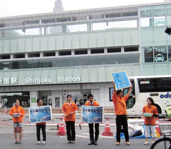 2016년 쿠마모토 지진 구호와 복구를 지원하기 위해 자원봉사자들이 신주쿠 역 앞에서 모금활동을 펼치고 있다.