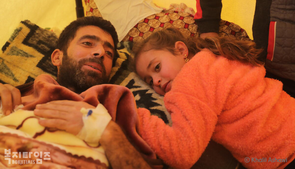 디나(6세, 가명)가 부상에서 회복 중인 아버지 루트피(가명)를 껴안고 있다.(사진=Khalil Ashawi, 세이브더칠드런)
