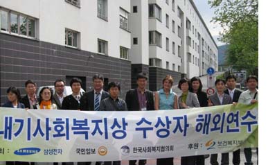 여성·청소년 복지시설(뒤에 보이는 건물)을 방문한 후 참가자들이 기념 촬영을 하고 있다.
