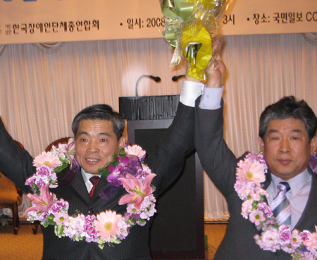 박덕경 신임 공동대표(왼쪽)와 임통일 전 공동대표가 손을 맞잡아 참석자들에게 인사하고 있다.